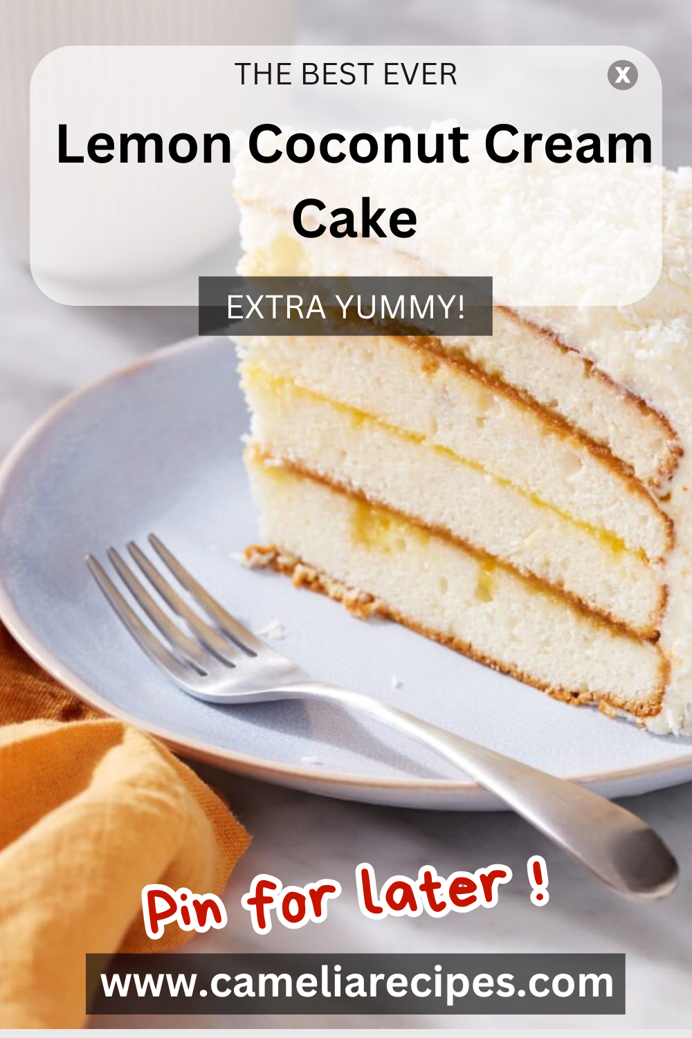 A sunny Lemon Coconut Cream Cake sits on a white plate, adorned with a glossy lemon glaze that cascades down the sides. The creamy coconut filling peeks through the layers, adding richness and contrast. Toasted shredded coconut and fresh lemon slices decorate the top, adding charm and elegance.